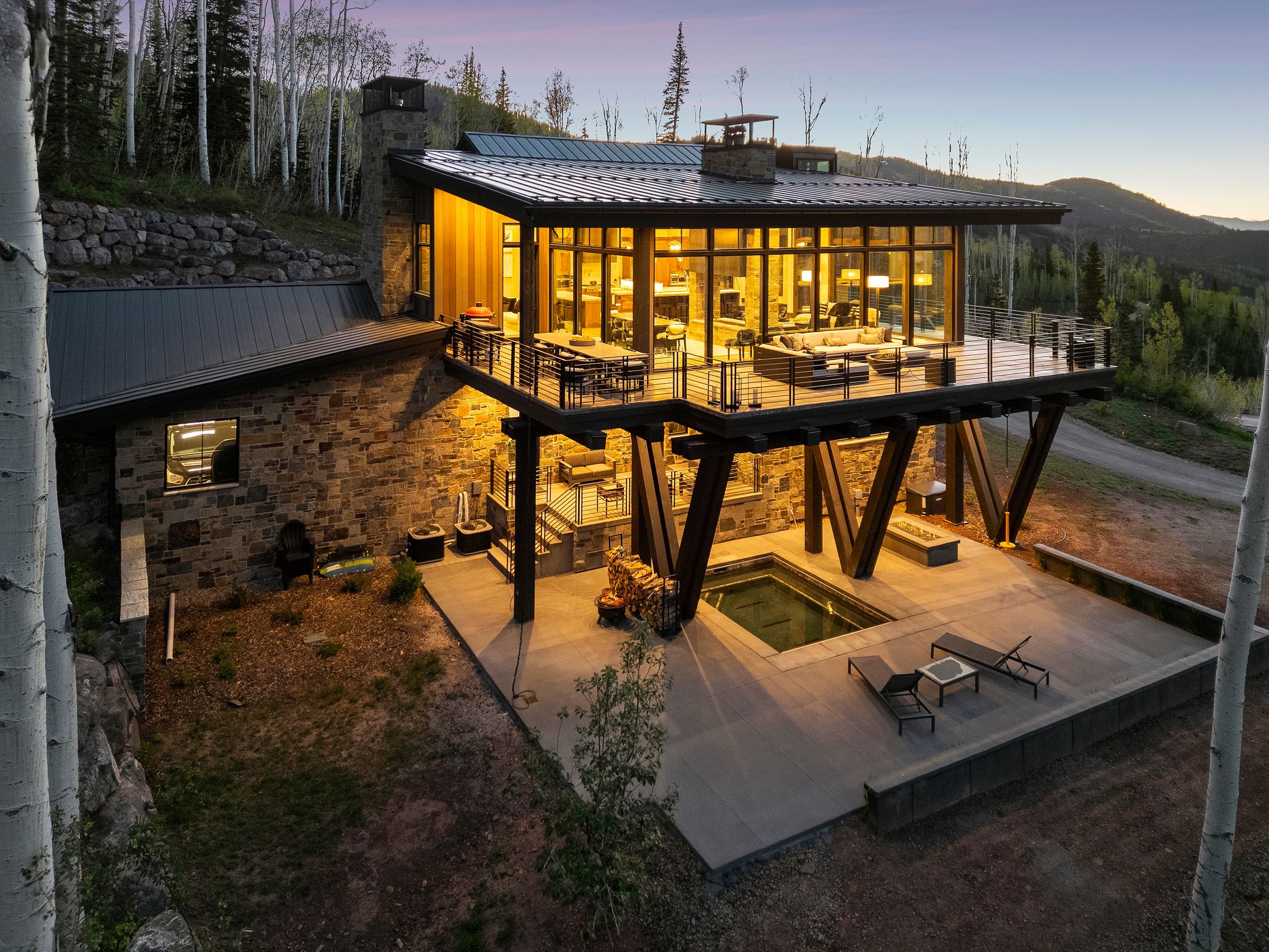 Modern mountain residence featuring a stone and wood exterior with a metal roof