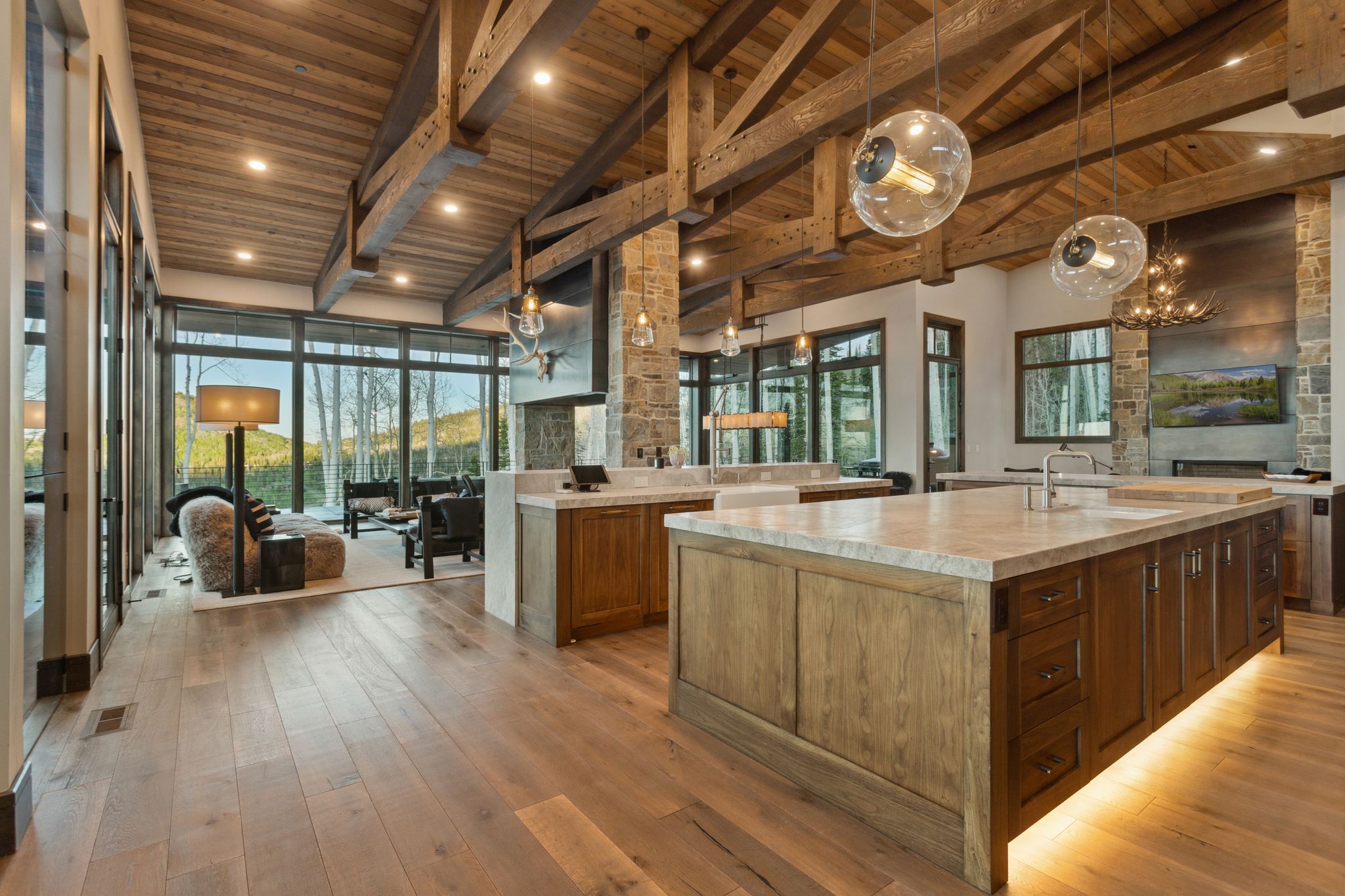 Open concept interior featuring wide plank wood-finish flooring and a vaulted wood-paneled ceiling with exposed beams