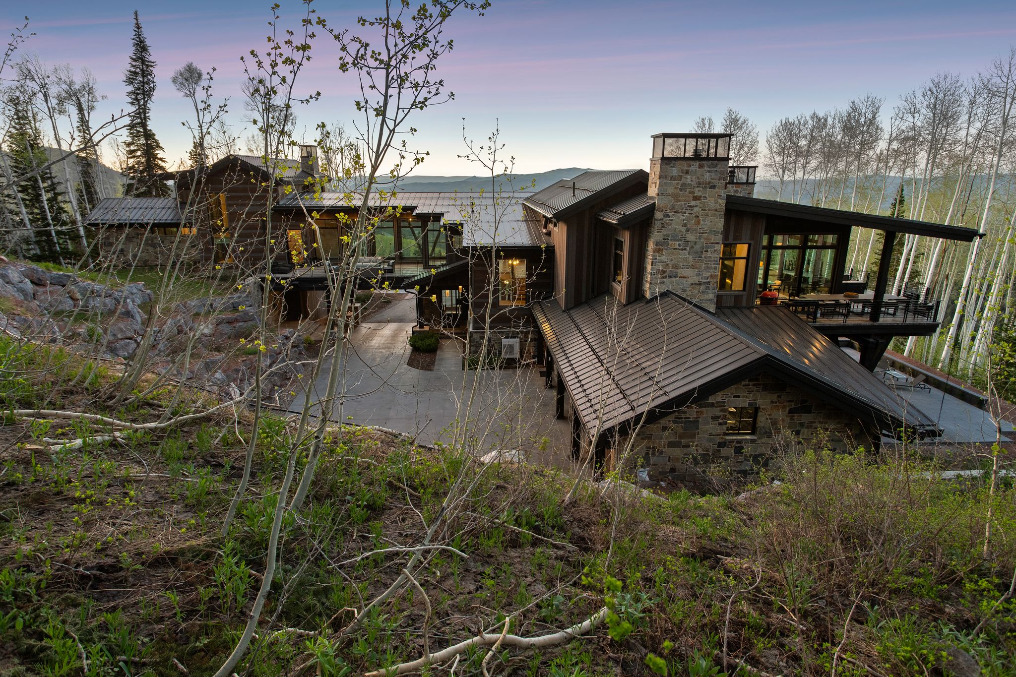 Multi-level residence featuring a stone and wood exterior with a prominent stone chimney