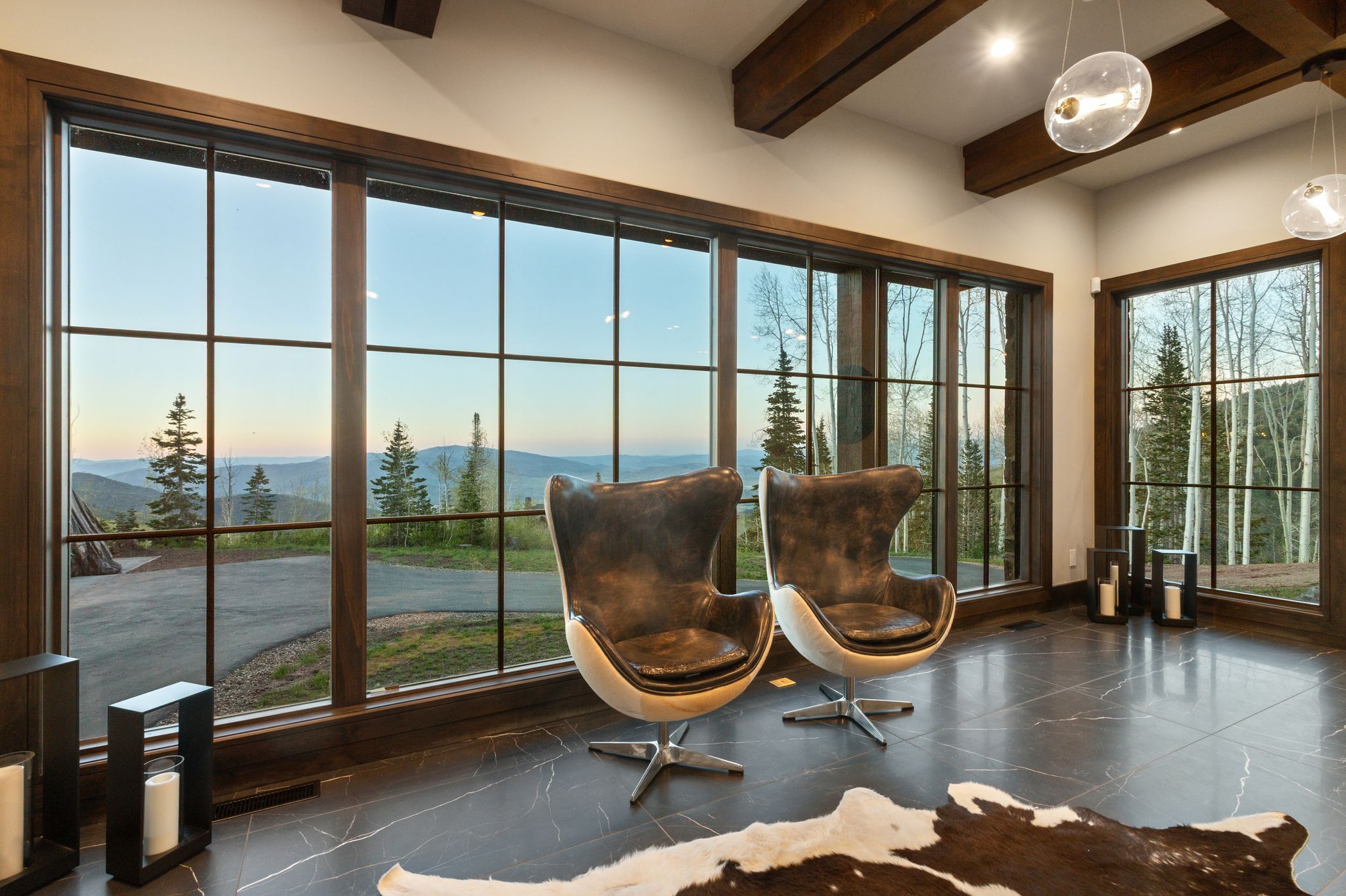 Floor-to-ceiling windows with grid patterns frame scenic mountain and forest views