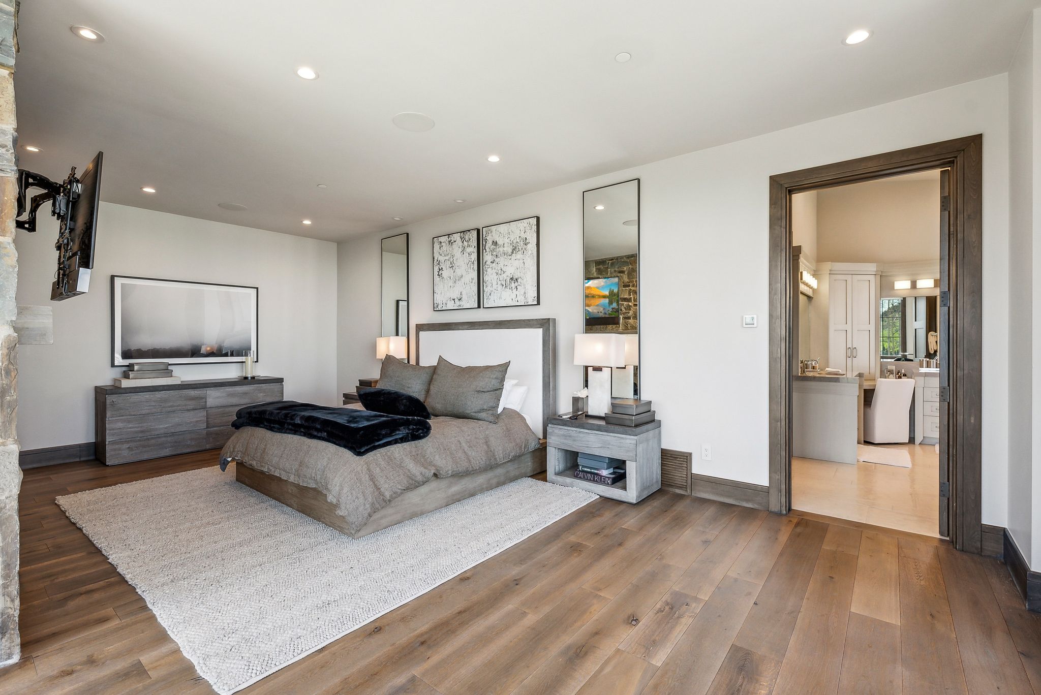 Spacious room featuring wide plank wood-finish flooring, recessed lighting, and a stone accent wall