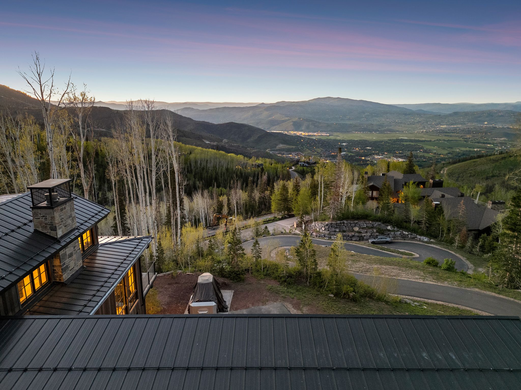 Expansive mountain landscape featuring a winding paved road and mature trees