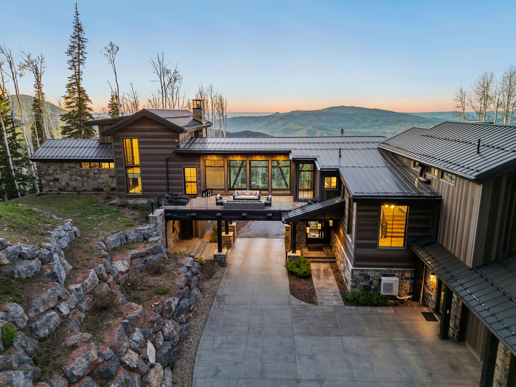 Contemporary mountain residence featuring multiple levels, a prominent deck, and extensive natural stone and wood siding