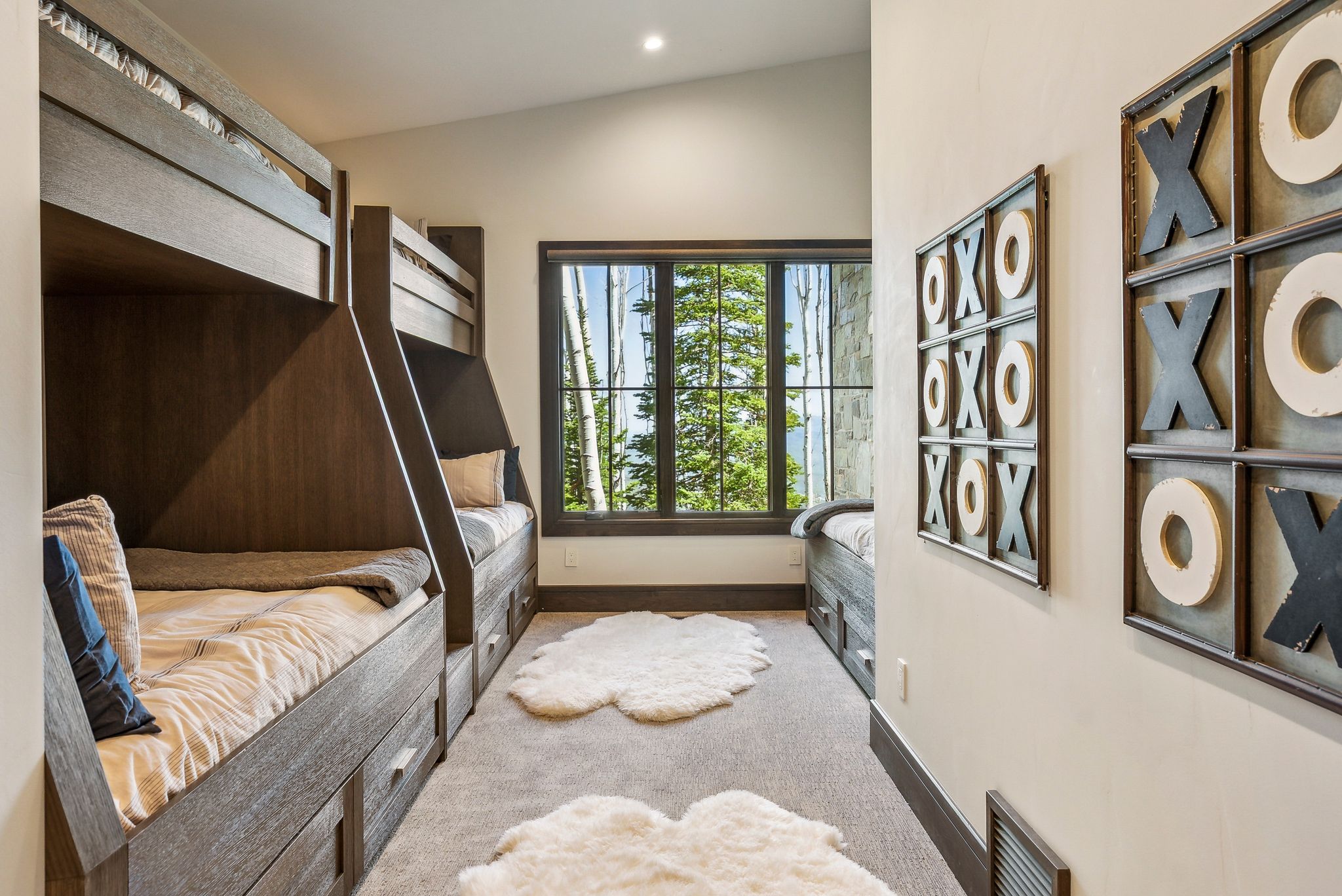 Room featuring built-in bunk beds with integrated storage drawers, a vaulted ceiling, and a large window overlooking a wooded landscape