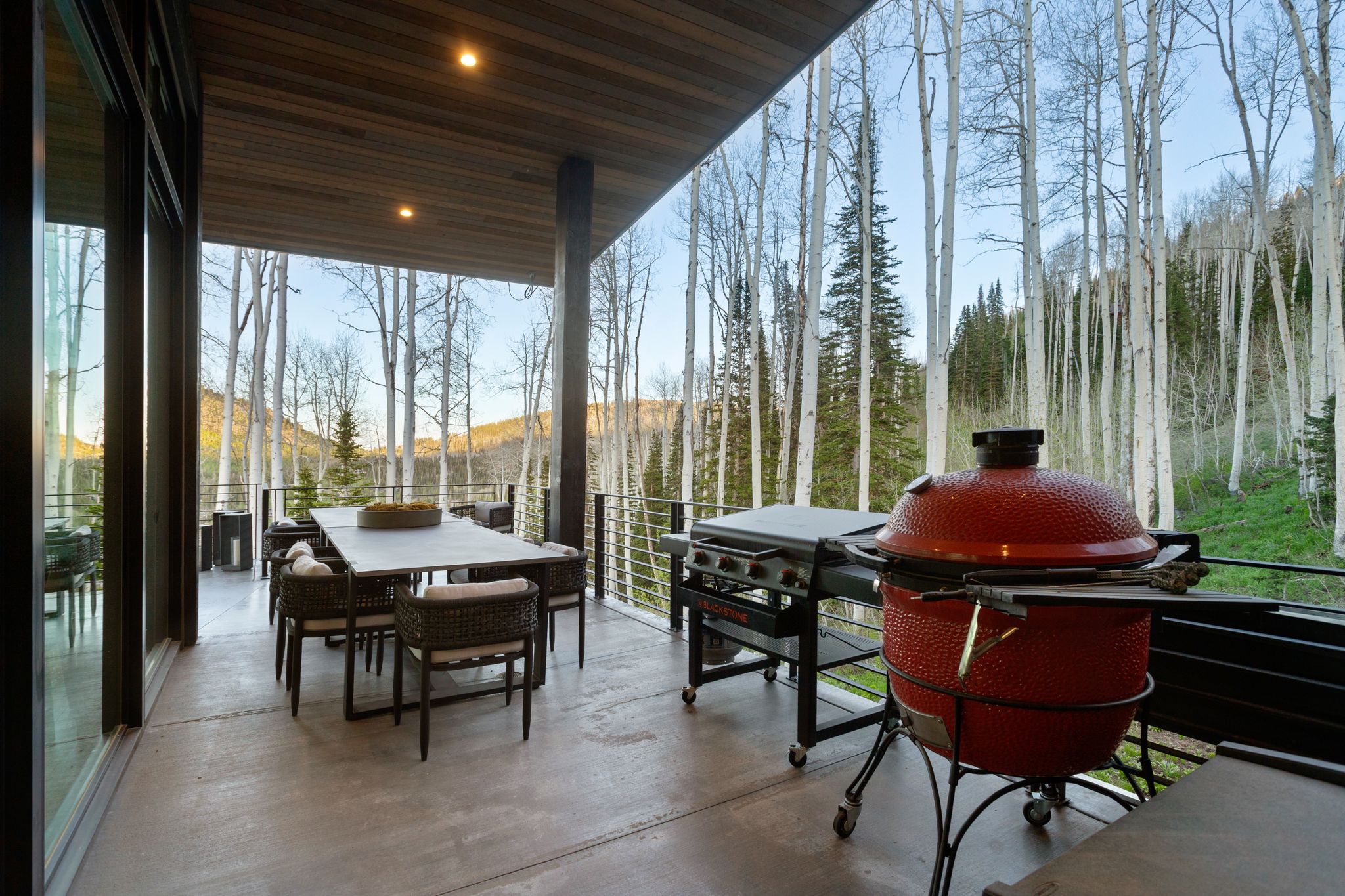Expansive outdoor deck featuring a concrete floor, wood-paneled ceiling with recessed lighting, and a cable railing system