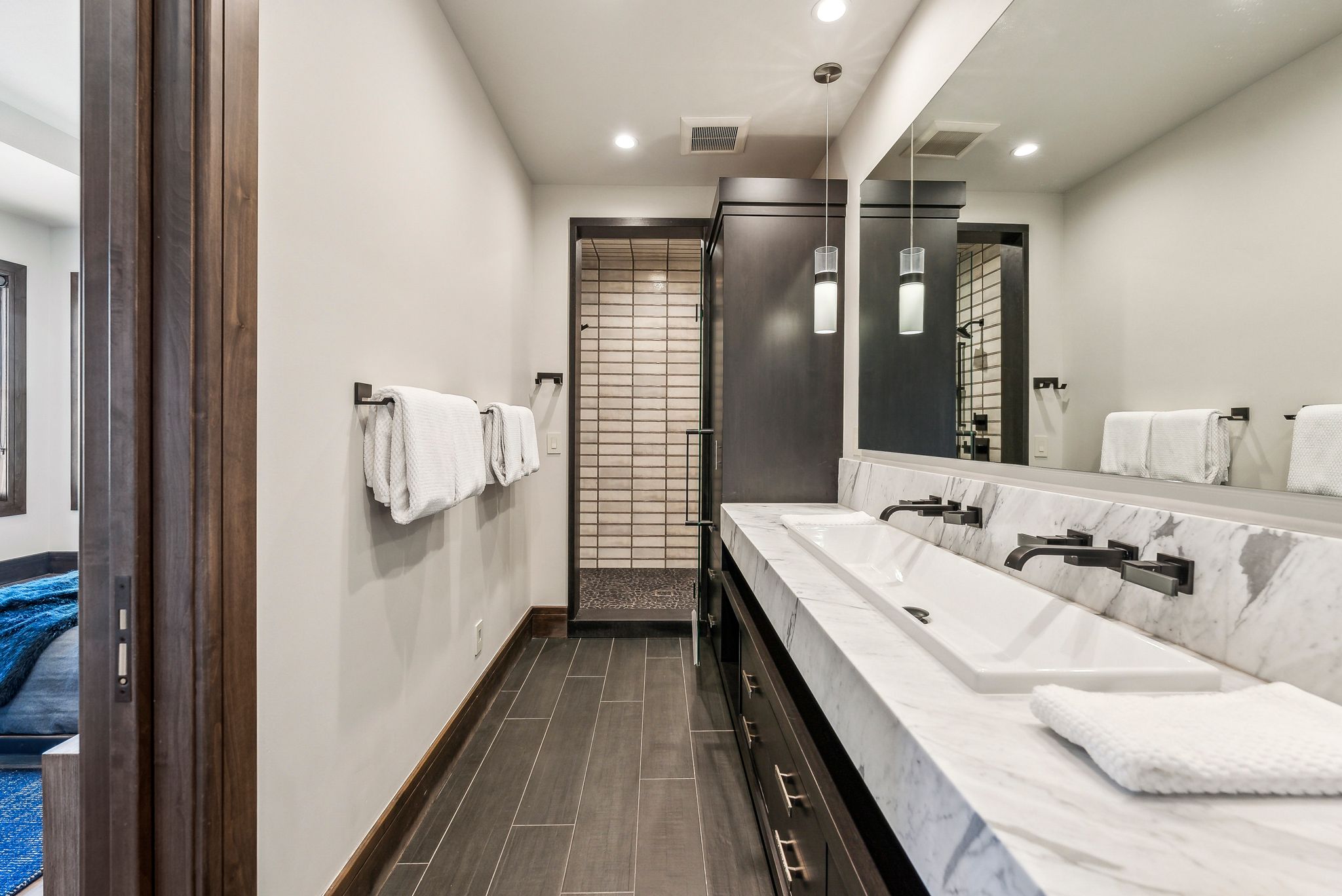 Dual vanity with a single integrated sink, marble countertop, and wall-mounted matte black faucets
