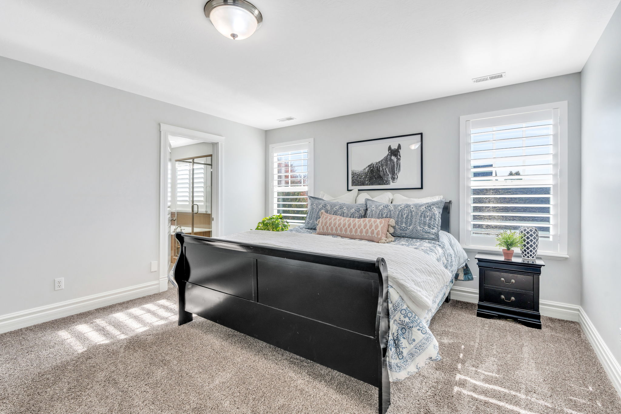 Primary bedroom with light carpet and ensuite bath