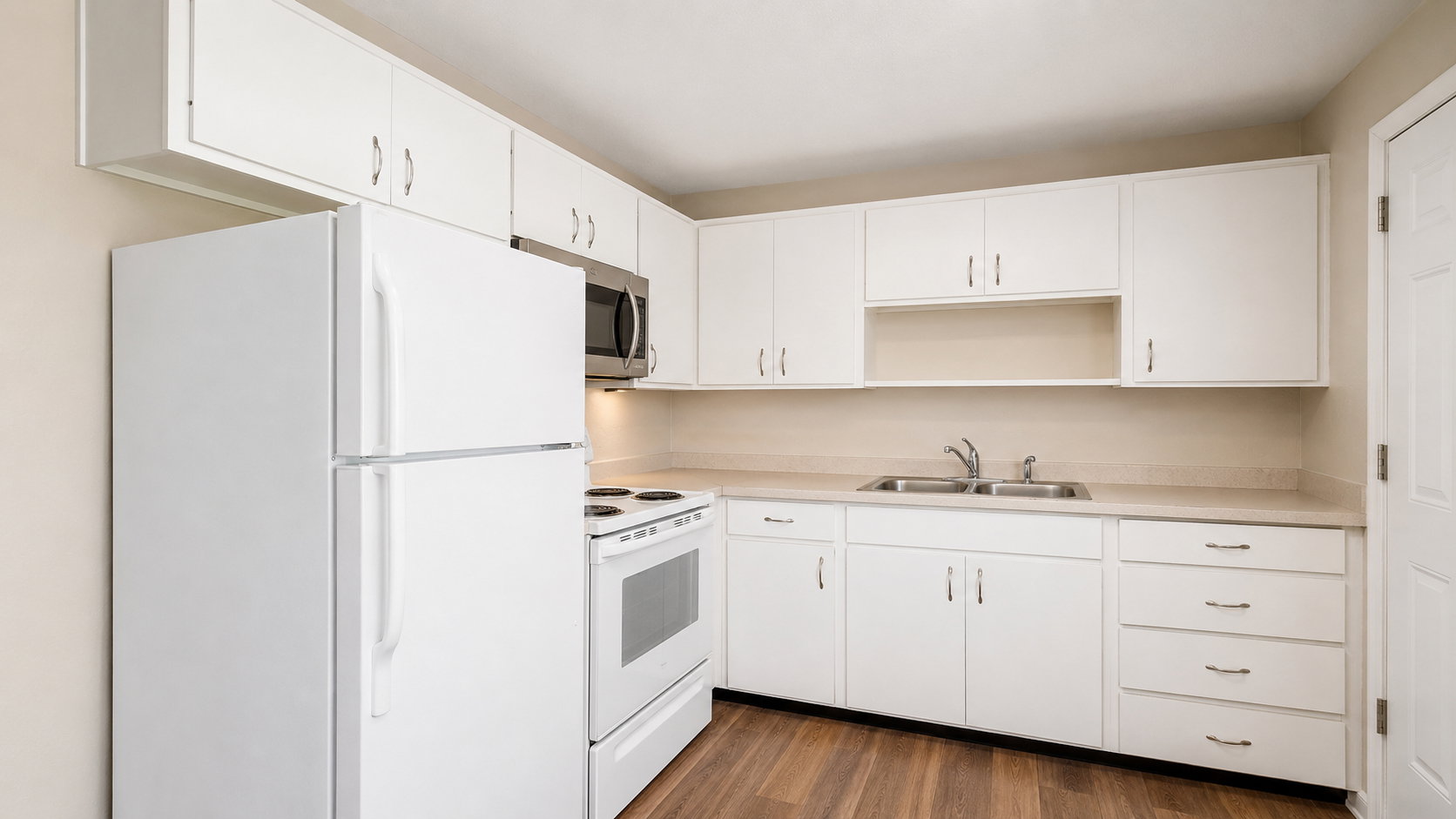 Kitchen featuring white cabinetry, light countertops, wood-finish flooring, a stainless steel microwave, and a white oven