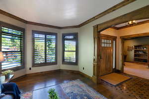 Entryway featuring a wood-panel door with glass lites, intricate wood-finish flooring with geometric inlay, and a substantial wood-trimmed archway
