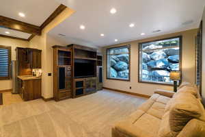 Spacious room featuring a built-in entertainment center, recessed lighting, and a wet bar with a stainless steel refrigerator