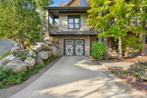 Stone facade property with a decorative garage door and a concrete driveway