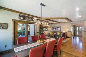 Dining area featuring a rectangular wood-finish table, wood-finish flooring, and a unique linear chandelier
