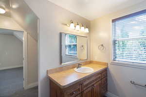 Bathroom vanity featuring a light-toned countertop with an integrated sink, brushed nickel faucet, and wood-finish cabinetry with multiple drawers and cabinet storage