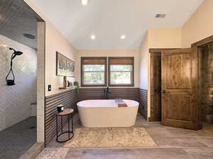 Freestanding soaking tub with a wall-mounted faucet, complemented by wood-finish wall paneling and two large windows