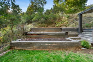 Tiered landscaping featuring wood-retaining walls, integrated garden beds, and steps leading to an elevated outdoor area