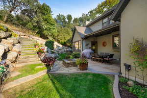 Expansive outdoor living area featuring a flagstone patio, stone fire pit, and terraced rock landscaping with integrated steps