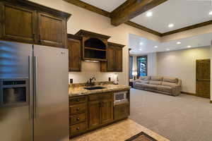 Lower-level living area featuring a wet bar with a stainless steel refrigerator, built-in microwave, and wood-finish cabinetry