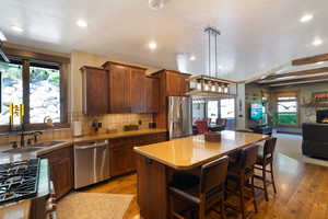 Kitchen featuring wood-finish cabinetry, stainless steel appliances, and a central island with bar seating