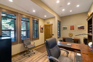 Dedicated workspace featuring wood-finish flooring, recessed lighting, and a solid wood door