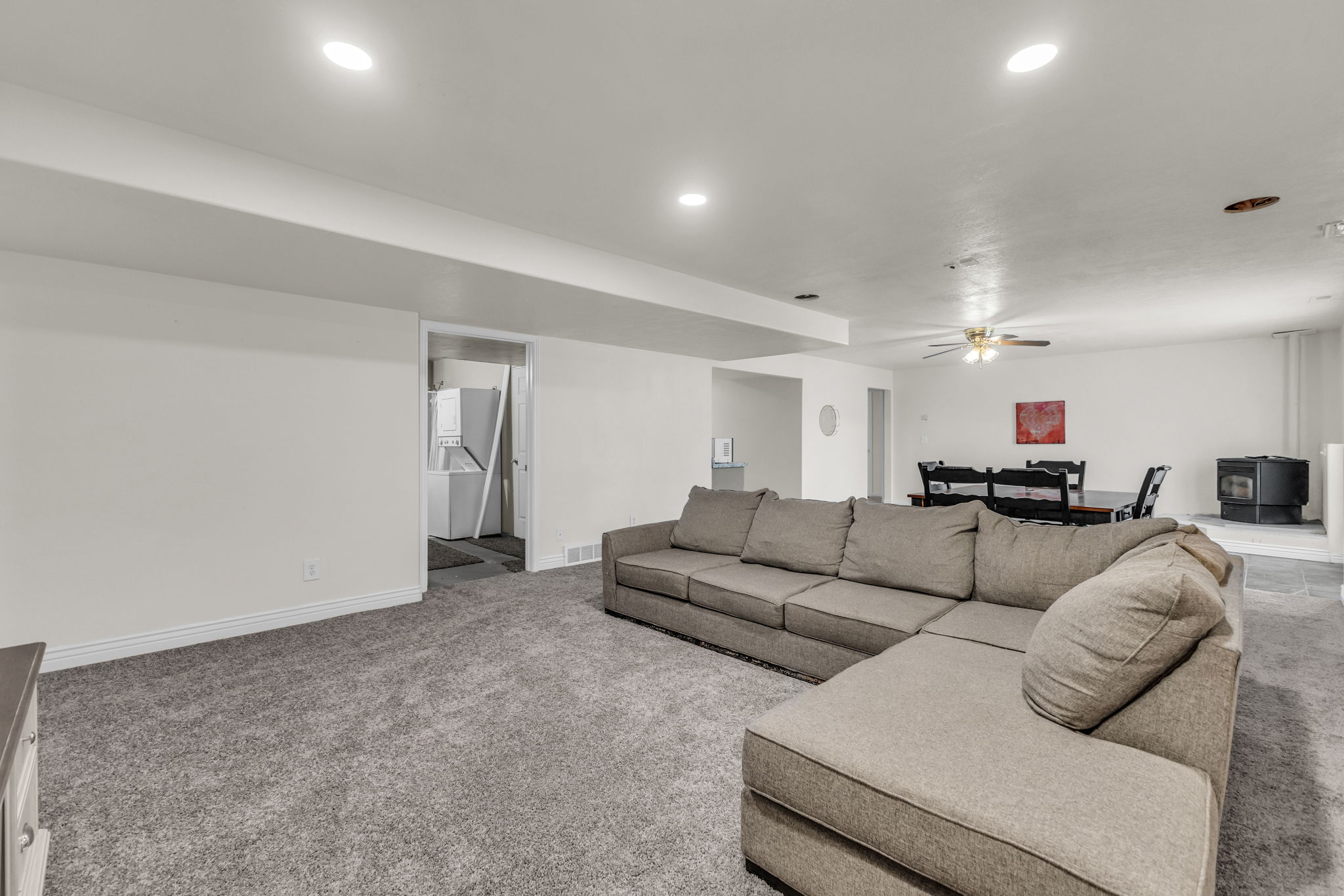 Spacious lower-level area with recessed lighting and neutral gray carpeting throughout