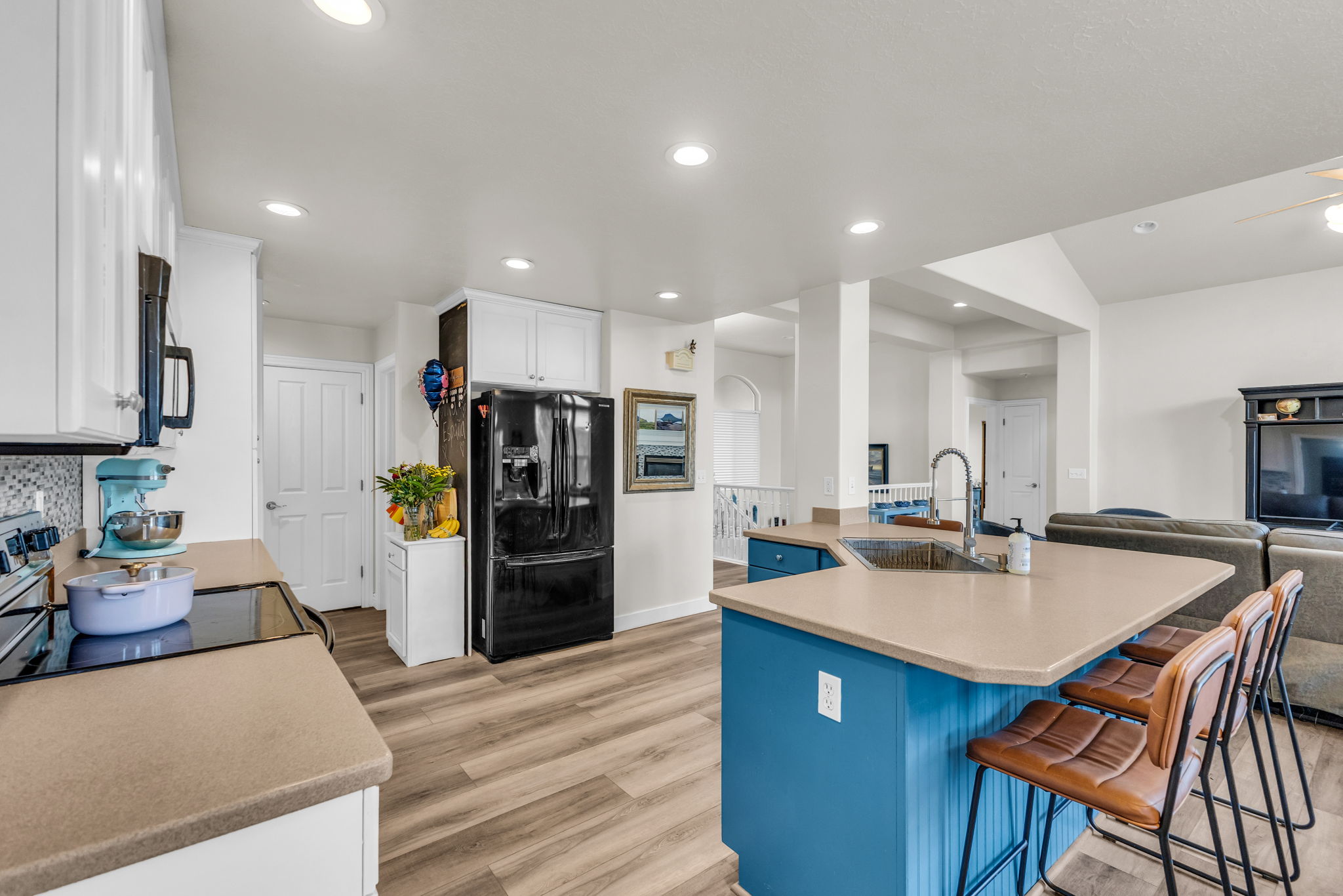 Open-concept kitchen with recessed lighting, light wood-finish flooring, and a central island featuring a stainless steel sink and breakfast bar seating