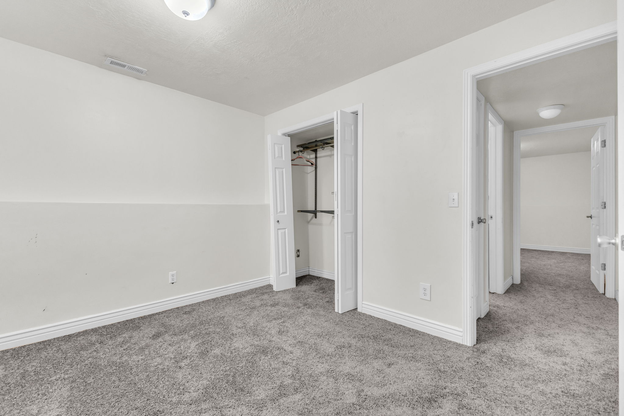 Neutral-toned room featuring grey textured carpeting and white baseboards
