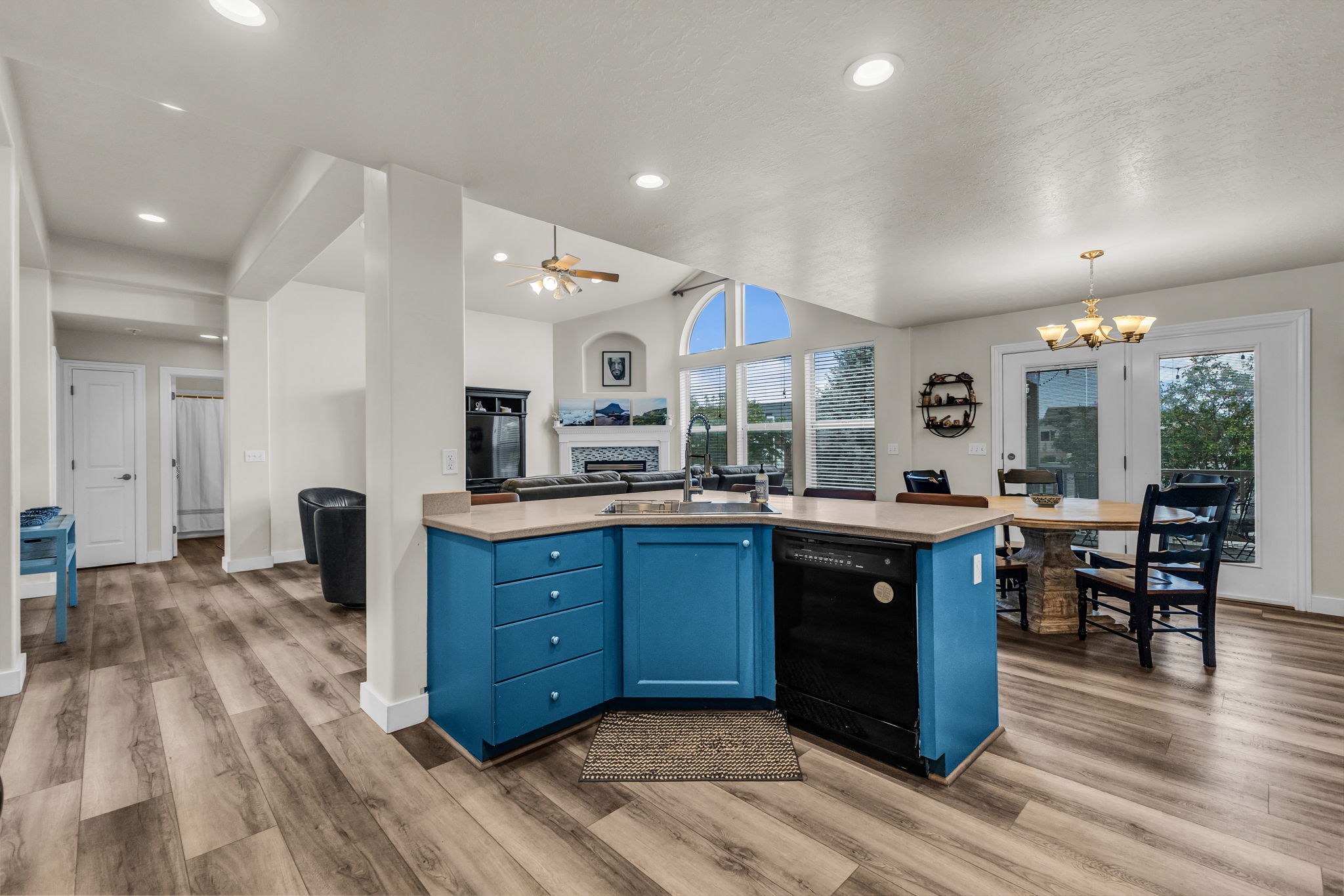 Kitchen island with blue cabinetry, a built-in sink, and dishwasher, complemented by wood-finish flooring