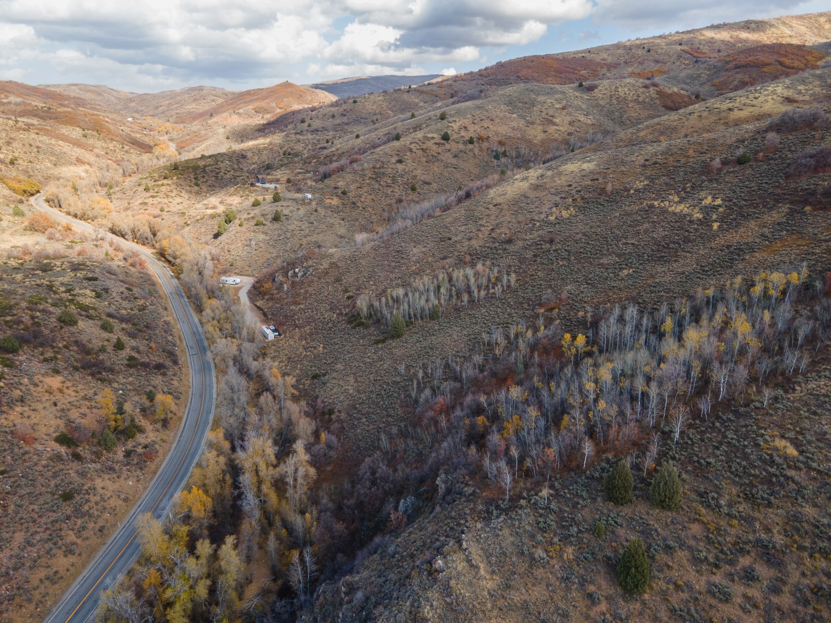 Winding paved road traversing mountainous terrain with abundant natural foliage