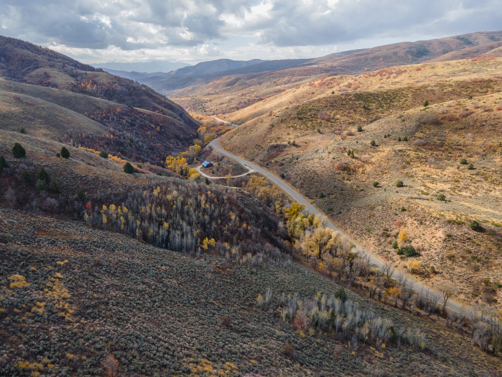 Expansive mountain property featuring varied topography, a paved roadway, and mature deciduous trees with autumn foliage