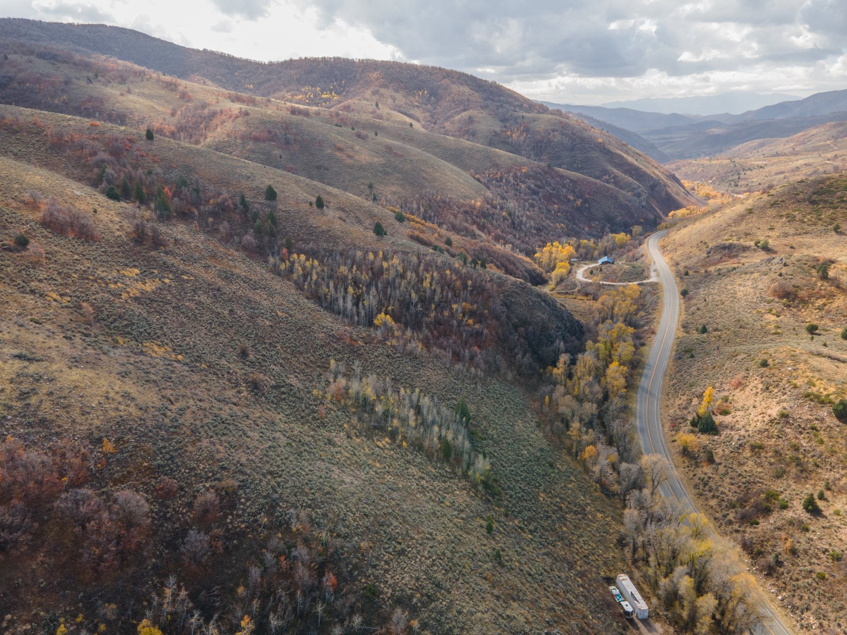 Winding road traversing a mountain valley with autumn foliage