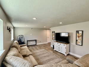 Recessed lighting illuminates this space featuring wood-finish flooring and neutral wall tones