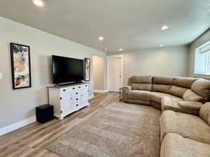 Spacious entertainment area featuring wood-finish flooring, recessed lighting, and light gray wall tones
