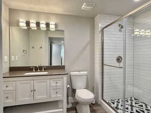 Bathroom featuring a glass-enclosed shower with white subway tile and a patterned floor, a single vanity with shaker-style cabinetry, an integrated sink, and a large mirror with a four-light fixture