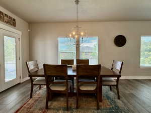 Dining area featuring wood-finish flooring, a contemporary spherical chandelier, and multiple windows with blinds