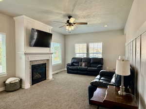 Living room featuring a fireplace with a stacked stone surround and a white mantel, complemented by light-colored carpeting