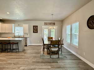 Open-concept living space featuring wood-finish flooring, a kitchen island with seating, white cabinetry, and stainless steel appliances
