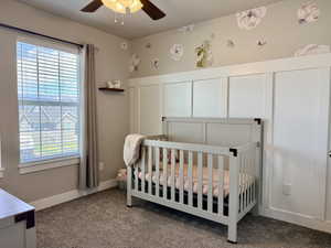 Board and batten accent wall with integrated trim, neutral wall color, ceiling fan with integrated lighting, window with blinds, and durable carpeting