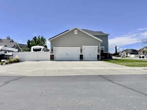 Stucco and siding exterior featuring a two-car garage with white paneled doors, stone accents, and exterior lighting fixtures