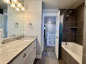 Bathroom featuring a vanity with a light-toned countertop and an integrated sink, a rectangular mirror, and a multi-bulb light fixture