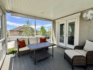 Screened patio featuring a beadboard ceiling, composite decking, and double glass-paneled doors