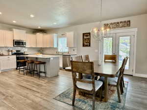 Open-concept kitchen and dining area featuring wood-finish flooring, recessed lighting, and a contemporary chandelier