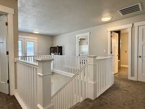Upper-level landing featuring white baluster railings and recessed lighting