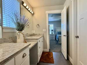 Double vanity with integrated sinks, granite countertops, white cabinetry, and brushed nickel hardware