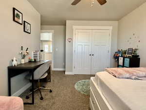 Carpeted room featuring a white paneled closet door, a flush-mount ceiling fan, and light-colored walls