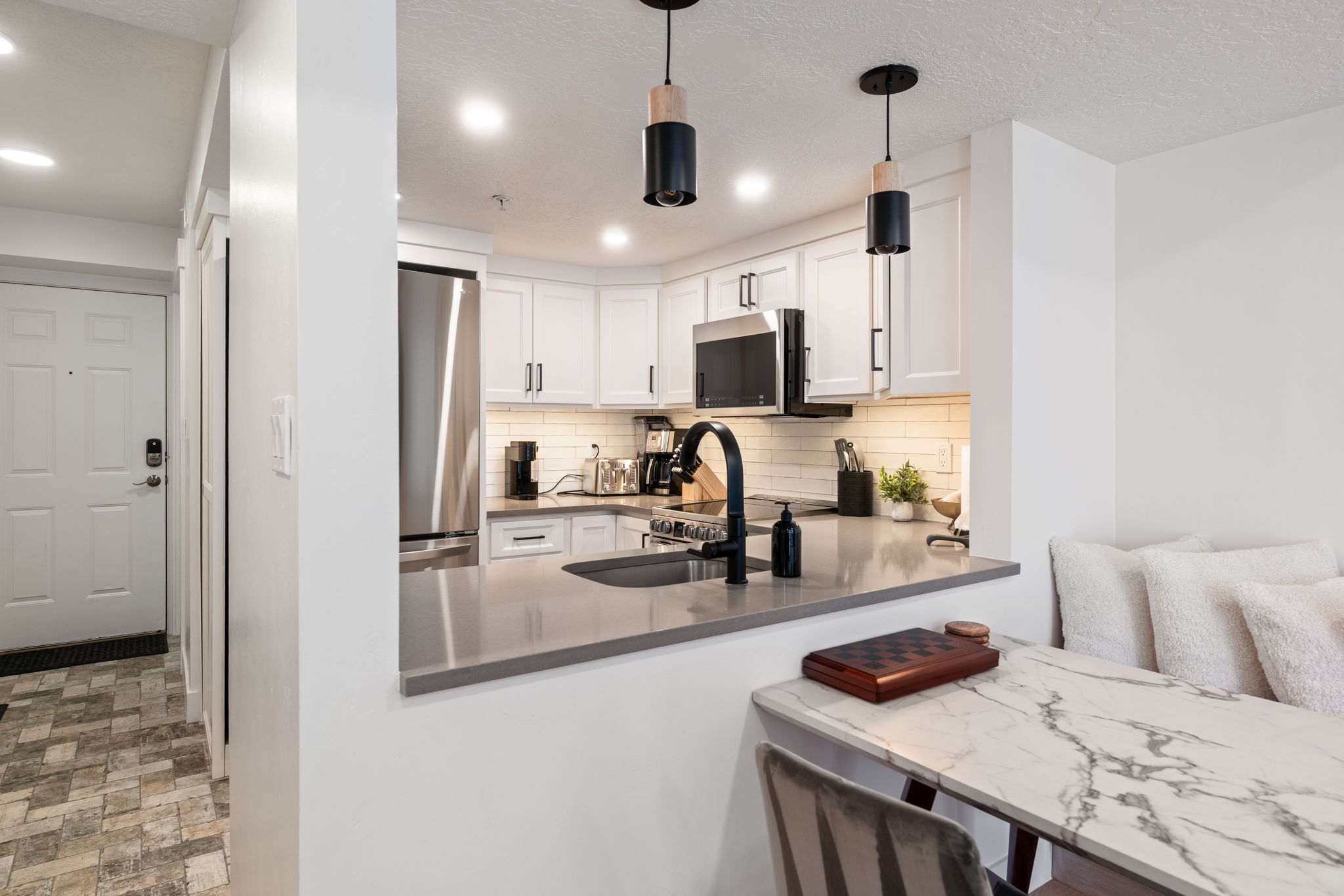 Contemporary kitchen featuring white shaker cabinetry, stainless steel appliances, and a grey countertop with an undermount sink