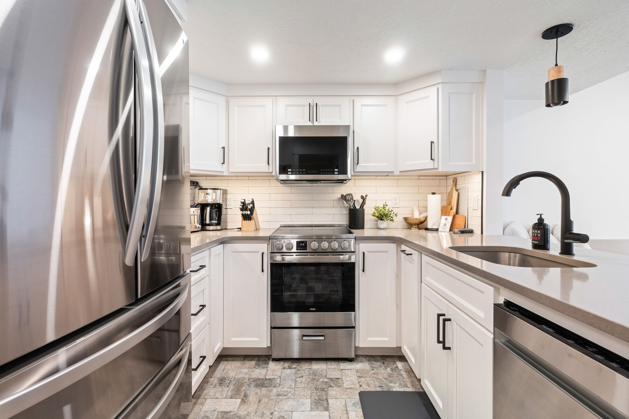 Kitchen featuring white cabinetry, stainless steel appliances, a subway tile backsplash, light-toned countertops, and mosaic-style flooring