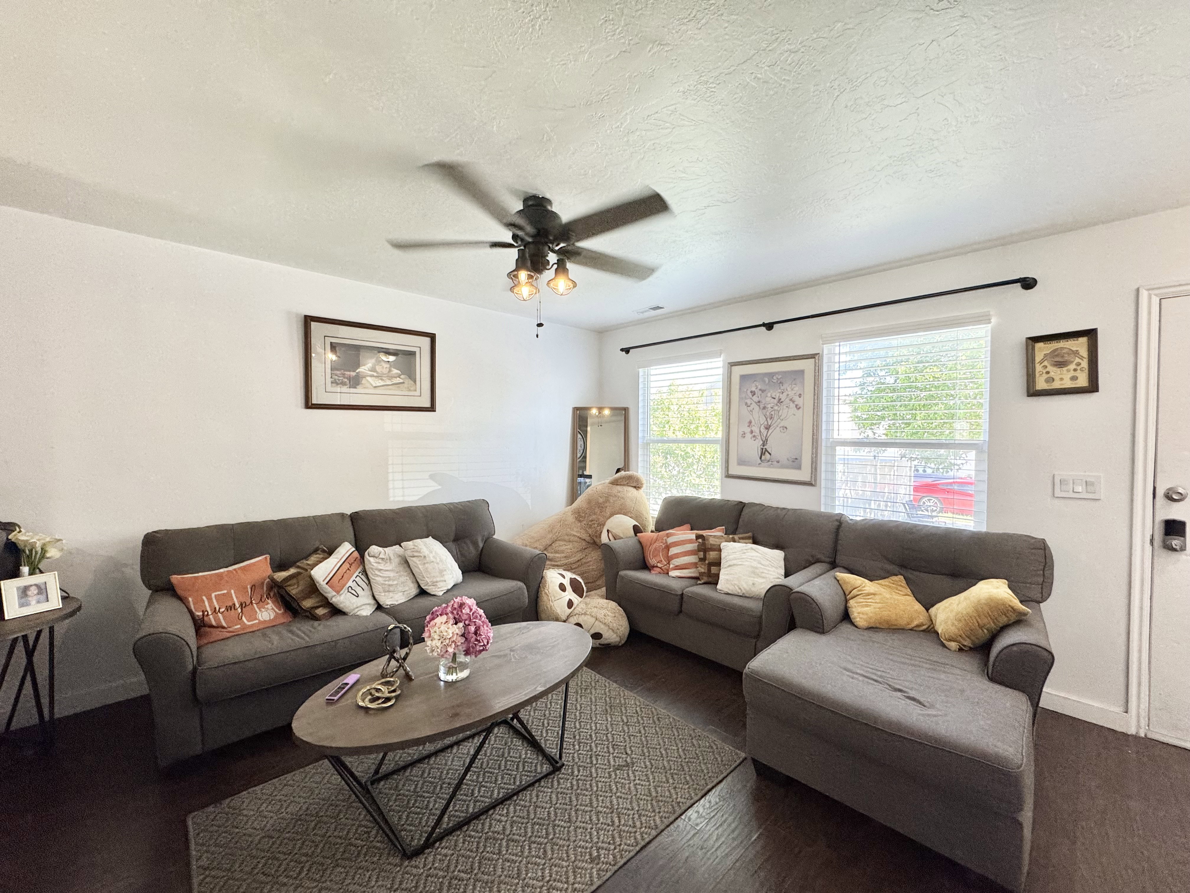 Spacious living area featuring wood-finish flooring and a ceiling fan