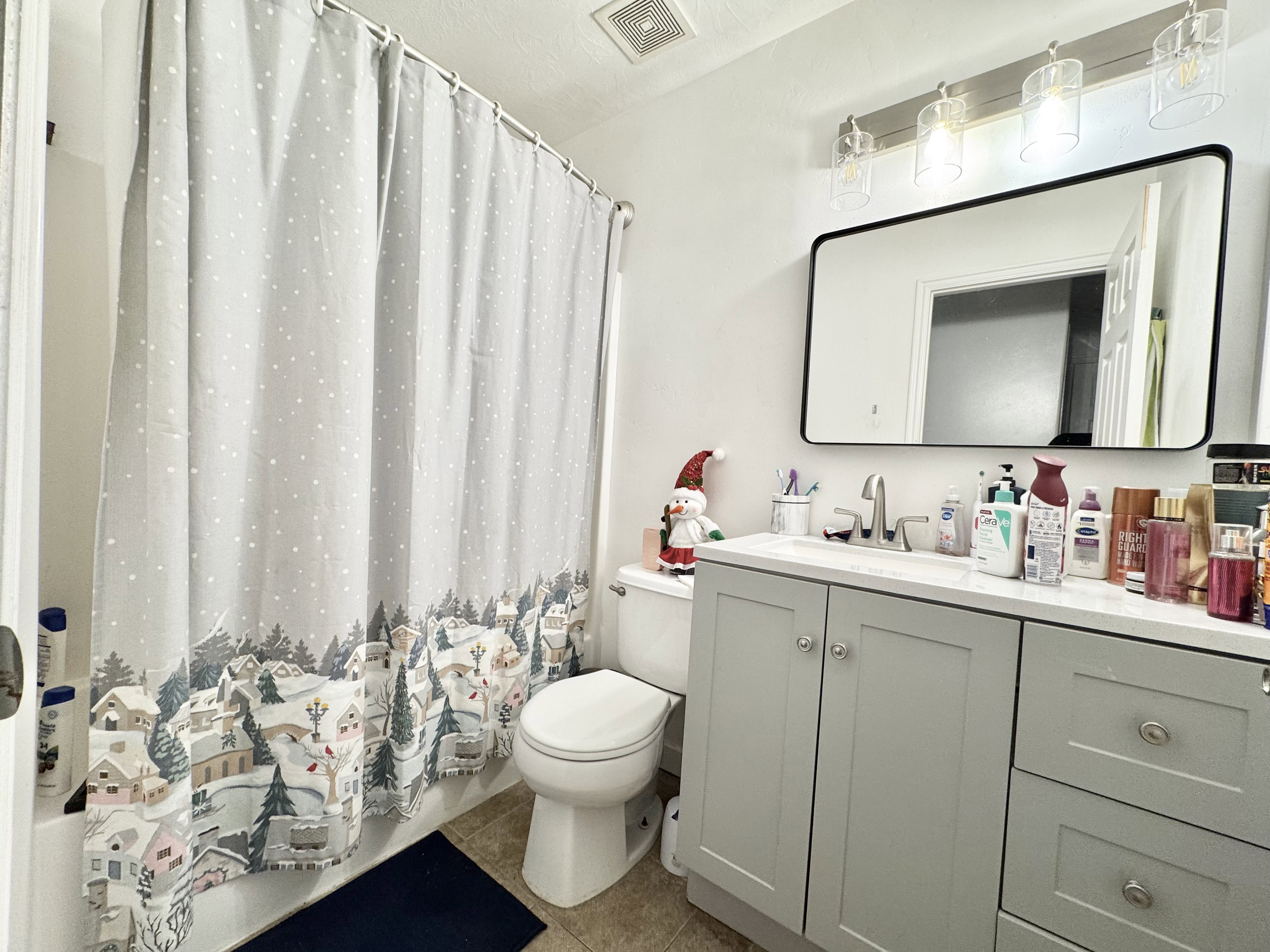 Bathroom featuring a light-toned vanity with cabinet storage and drawers, a rectangular undermount sink, and a chrome faucet