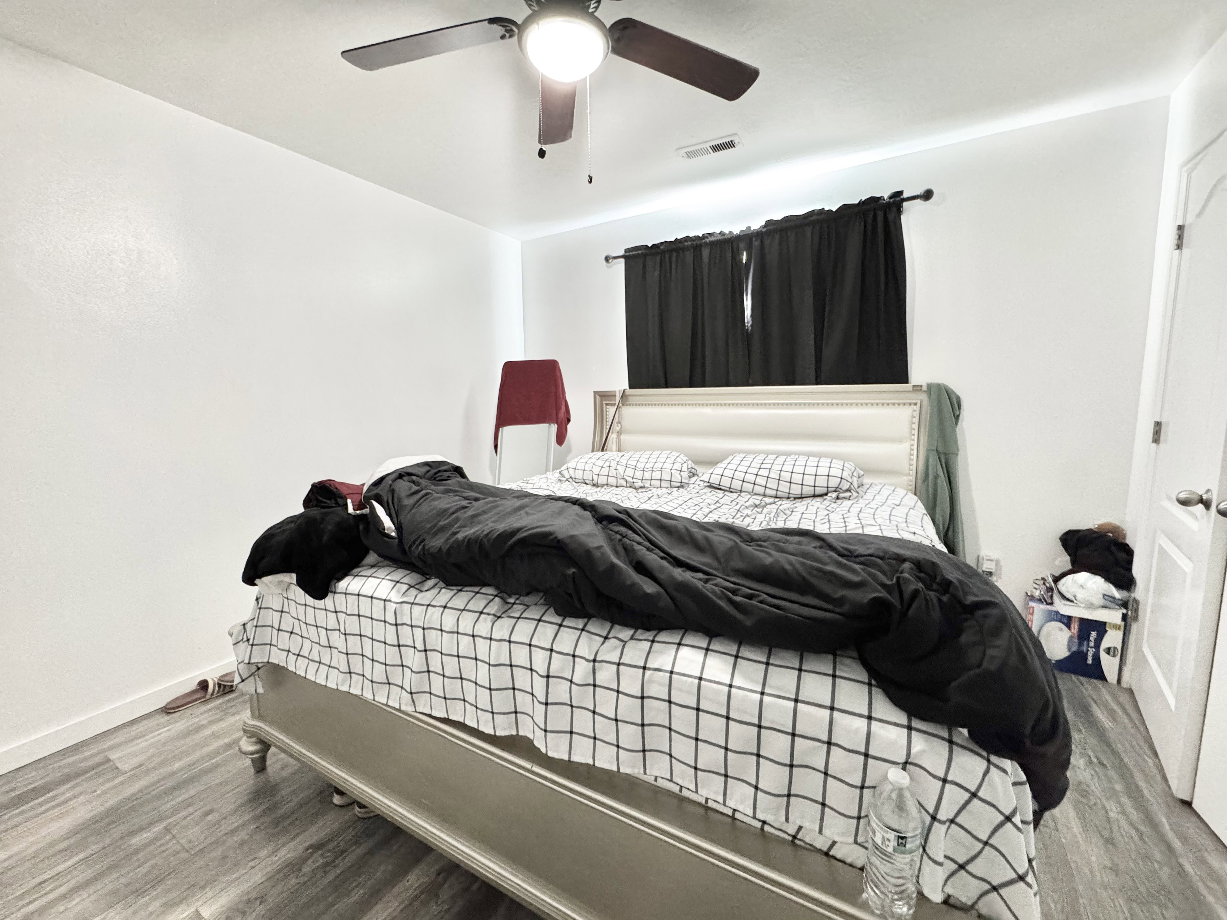 Room featuring wood-finish flooring, a ceiling fan with integrated lighting, and a window with dark curtain rods