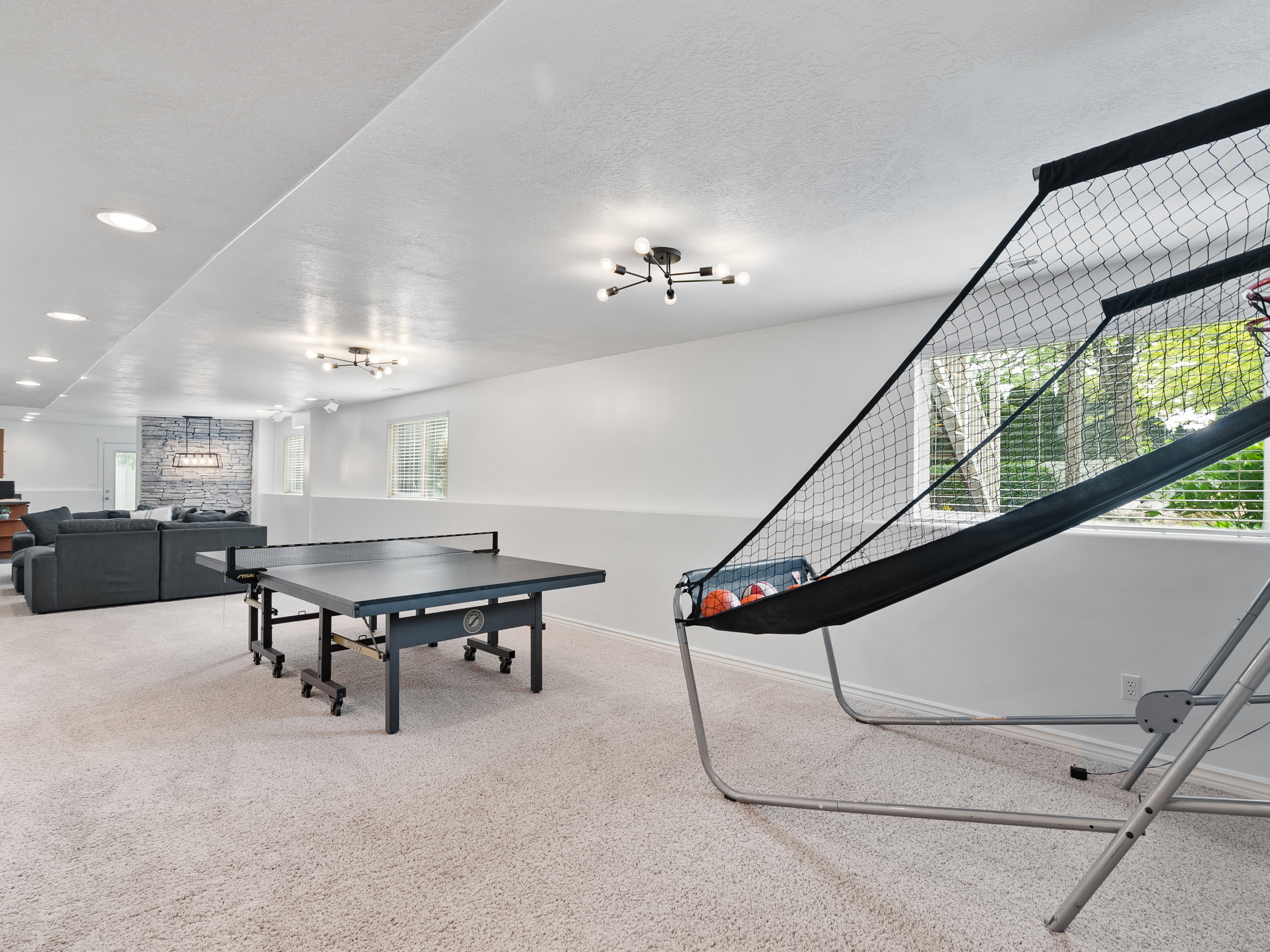 Expansive lower-level recreational space featuring light-toned carpeting and recessed lighting